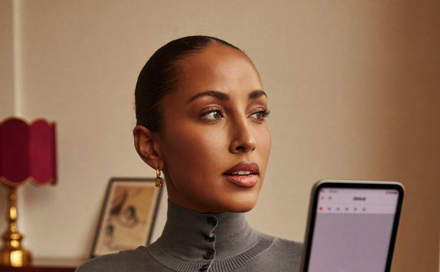 A calm, confident woman in warm natural light, looking at a tablet before a considered decision
